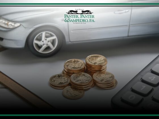 Stacked coins with car and calculator on desk, representing uninsured accident costs and financial liability